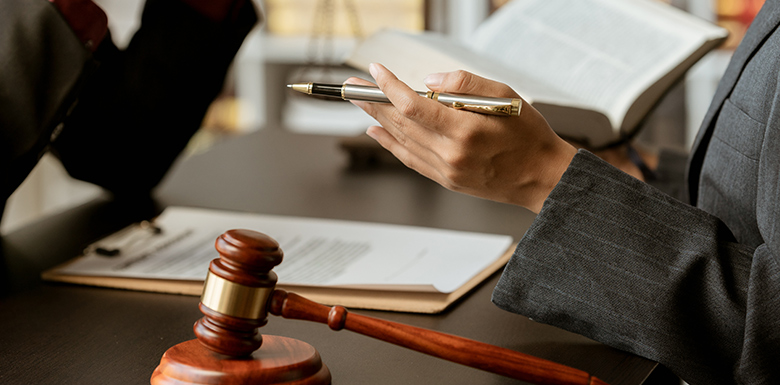 Close up view of 2 people sitting at a desk reviewing legal documentation with paper and books on the table