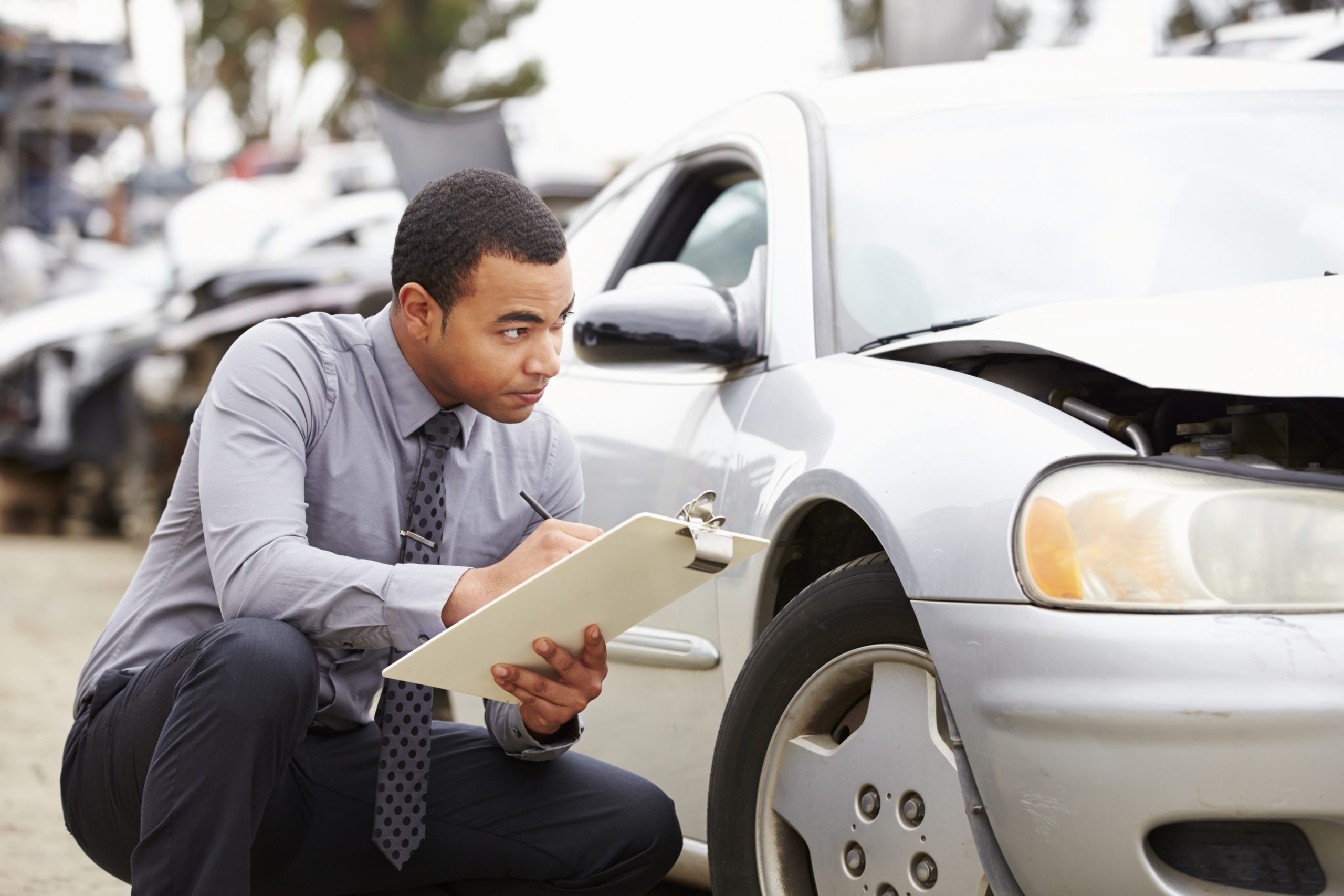 Man inspecting damage on car with clipboard