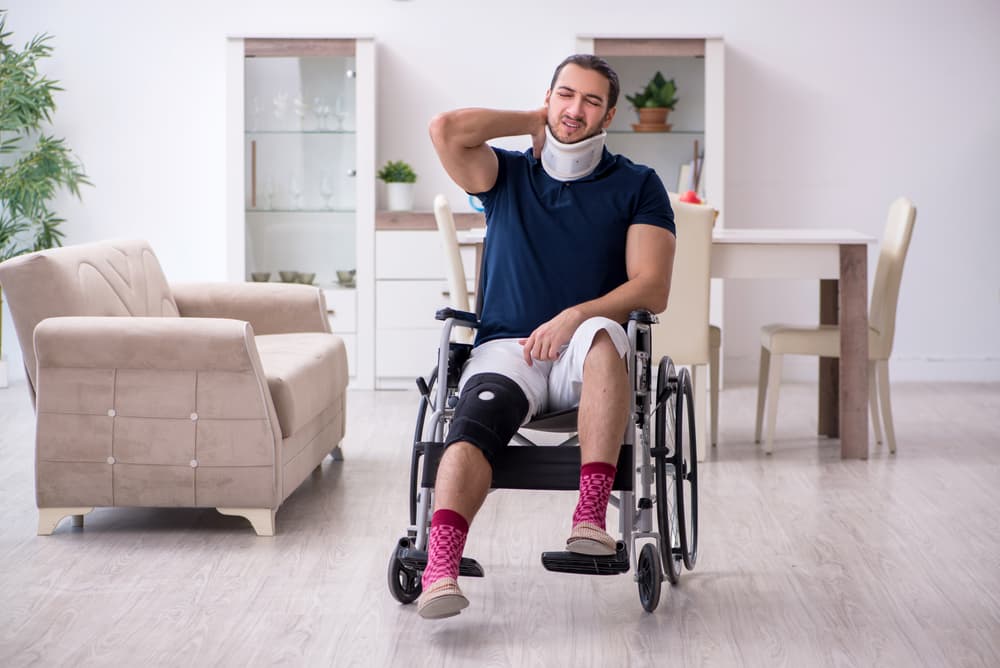 After car accident a injured young man in a wheelchair, experiencing pain and discomfort at home.