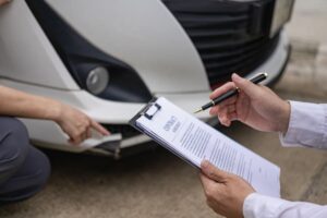 Insurance worker checks damaged car.