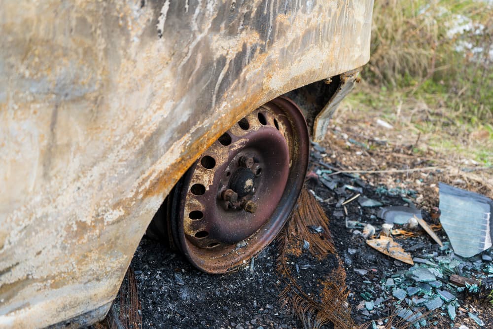 A car tire remaining after the vehicle has been completely burned, showing significant damage.